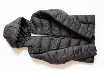 Black puffy winter jacket lies on a white background, fashionable winter clothes