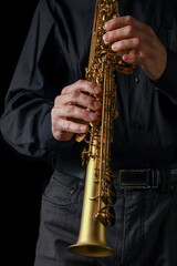 Naklejka premium soprano saxophone in hands on a black background