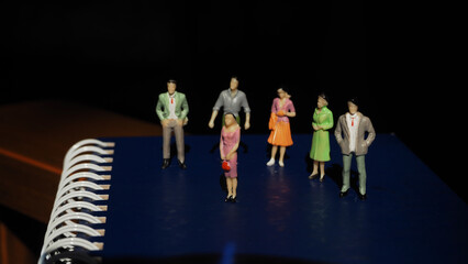 Group of miniature human figures of men and women standing on the book