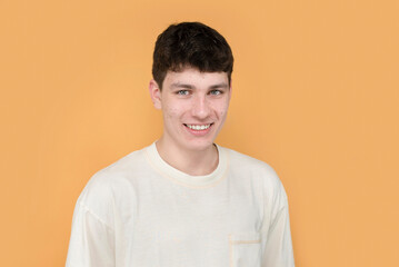 A young teenage boy has pimples and black dots on his face, but he is not shy and smiles sincerely,...