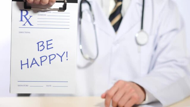 Physician in white uniform with stethoscope on his neck shows prescription card with words be happy, giving directions, disease treatment, be healthy, medicine. Close up, shallow DOF, 4K Ultra HD.