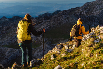 group of two mountaineers with backpack and trekking poles hiking up a mountain peak. sport, adventure and outdoor activity. weekend activities.