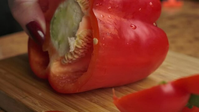 A knife cleans the insides of a red pepper bell