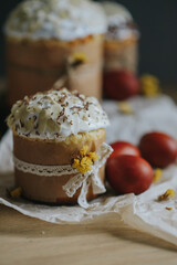 Traditional ukrainian easter cake with white swiss meringue. Spring daffodil and colorful painted eggs. Homemade food on the table