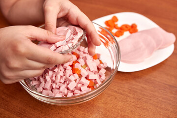 With the help of manual slicing, the cooked sausage is chopped for salad preparation.