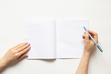 Female hands write in a notebook in a cage on a white background, blank pages and space for text
