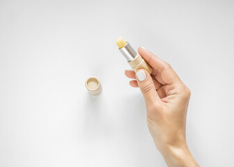 a female hand holds a lip balm in an eco-friendly cardboard package. lip care concept - obrazy, fototapety, plakaty