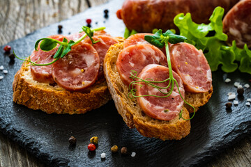 Sliced traditional Polish sausage kielbasa on bread with leafy greens