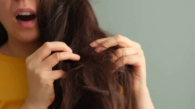 troubled brunette woman struggling with dry and knotted hair, hair mishap and the search for effective solutions to keep hair looking and feeling its best. Bad Hair Day.