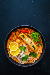 Tom Yum - Thai soup with salmon and rice noodles on wooden table
