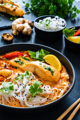 Tom Yum - Thai soup with salmon and rice noodles on wooden table

