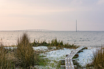 A small boardwalk to Apalachicola Bay with the bridge in the background at dusk. 
