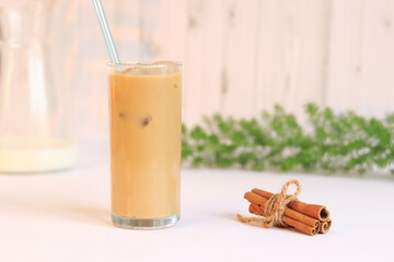 Ice latte. Coffee with ice and milk against the backdrop of a light kitchen, cinnamon, carafe with...