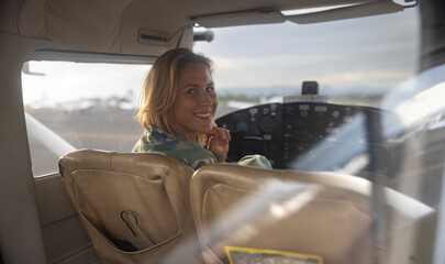 Woman pilot in military uniform pre-flight checking inside on a small aviation airplane. Flight pre-check inspection.