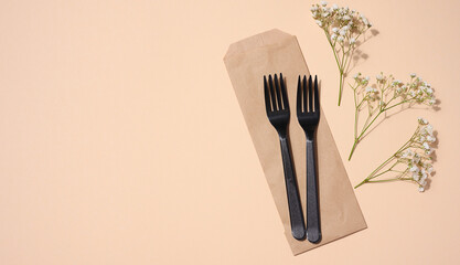Plastic black forks on a beige background, disposable picnic items, top view