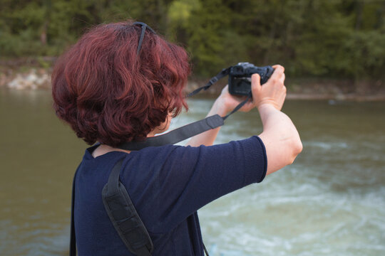 Female photographer holding mirrorless camera making outdoors photos