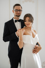 groom in a black suit tie and the bride in a bright studio