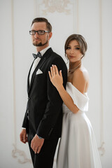 groom in a black suit tie and the bride in a bright studio