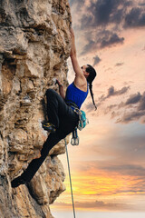 Woman climbing to reach the top of the mountain with beautiful sky at sunset. Concept of adventure and extreme sport.