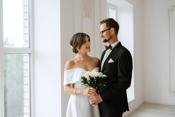 groom in a black suit tie and the bride in a bright studio