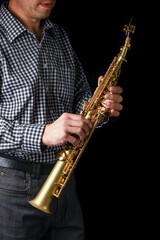 Fototapeta premium soprano saxophone in hands on a black background