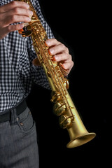 Obraz na płótnie Canvas soprano saxophone in hands on a black background