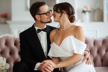 groom in a black suit tie and the bride in a bright studio