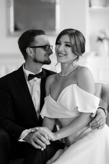 groom in a black suit tie and the bride in a bright studio