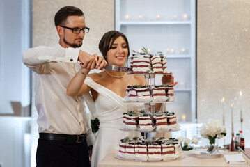 newlyweds happily cut and taste the wedding cake
