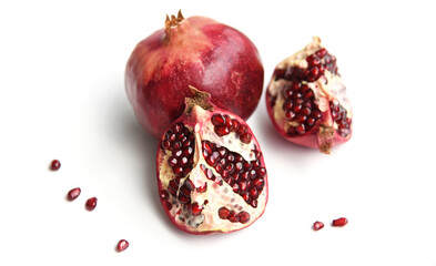 Whole pomegranate, pieces, and tempting semitransparent dark red kernels, isolated on white background, with shadows. Bright color of ripe fruit
 harvest, picked in Greek garden. Healthy food concept