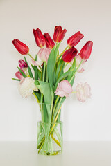 Spring flowers in a vase. Tulips in the house with white walls. Tulips and spring mood in the house