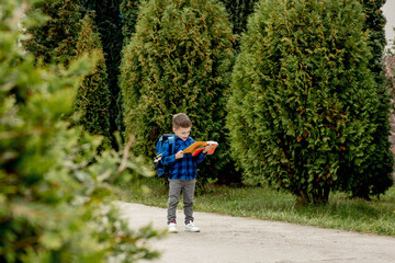 Fototapeta premium Little first grader with backpack looking the copybook, going home from school