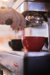 Bartender working on coffee machine in red cup and black cup