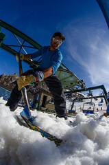 trabajador operario de aerosillas limpiando la nieve de la plataforma de abordaje en la cima de la montaña