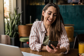 A female student uses her phone for studying while enjoying coffee at a restaurant