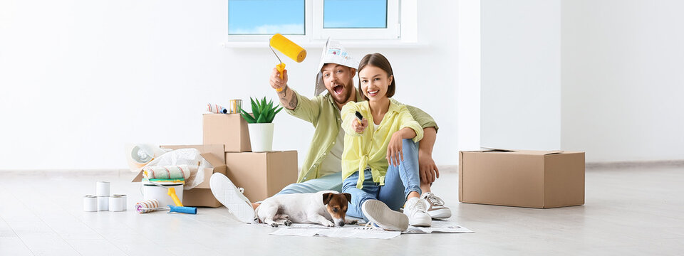 Happy young couple with cute dog making repair in their new house