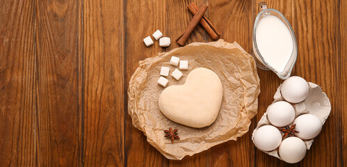 Fototapeta na wymiar Heart shaped dough and ingredients on wooden background with space for text