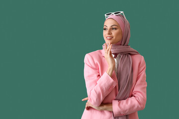 Stylish Muslim woman in pink hijab on green background