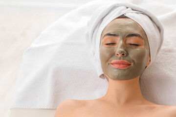 Young woman with applied clay mask in salon, closeup