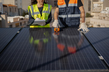 Cropped engineers teamwork testing urban Solar Panels with Multimeter and clipboard, receiving...