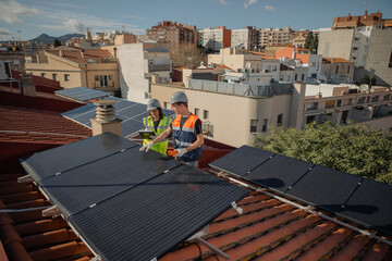Male engineer and female technician with yellow and orange vest during solar panel or cells...