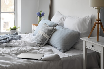 Interior of light bedroom with mirror and spring flowers in vase