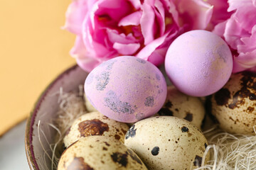 Bowl with Easter quail eggs and tulip flowers on beige table