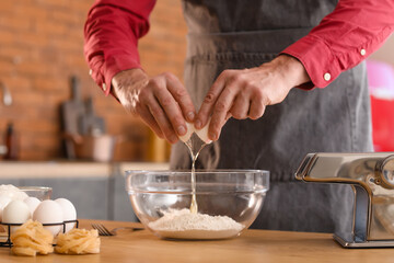 Obraz na płótnie Canvas Man making dough for pasta at table in kitchen, closeup