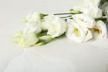Overturned vase with eustoma flowers and spilled water on light background, closeup