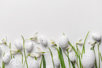 Fototapeta na wymiar Composition with Easter eggs and beautiful snowdrops on light background, closeup