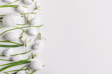 Composition with Easter eggs and beautiful snowdrops on light background, closeup