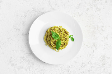 Plate with tasty pesto pasta on light grunge background - obrazy, fototapety, plakaty