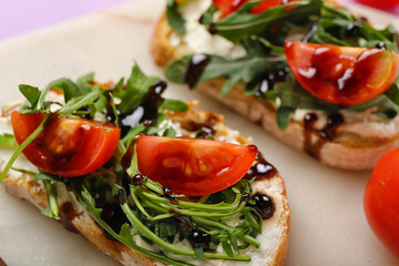 Fototapeta na wymiar Board of tasty sandwiches with cream cheese, arugula and tomatoes, closeup