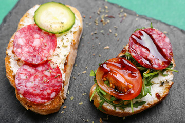 Slate board with tasty sandwiches, closeup